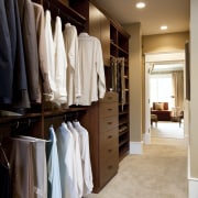 View of walk-in closet featuring shelving and storage. cabinetry, closet, floor, flooring, furniture, interior design, room, wardrobe, wood, brown, gray