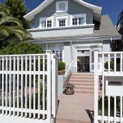Exterior view of the entrance way to this baluster, cottage, estate, facade, fence, gate, home, house, outdoor structure, picket fence, porch, property, real estate, residential area, siding, walkway, gray, white