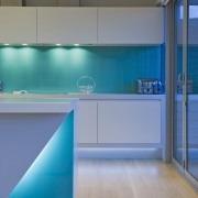 This sleek kitchen in a beach house features architecture, blue, floor, glass, house, interior design, kitchen, lighting, wall, teal, gray