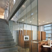 View of kitchen from stairwell featuring concrete floors, architecture, ceiling, daylighting, floor, glass, interior design, loft, wall, gray