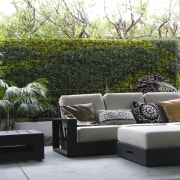 View of outdoor living space filled with mature couch, furniture, living room, outdoor furniture, outdoor structure, patio, table, wall