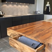 View of a contemporary kitchen which features island, countertop, floor, flooring, furniture, hardwood, interior design, product design, table, wood, wood flooring, wood stain, gray, black, orange