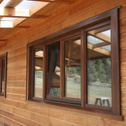 View of windows set into timber joinery by beam, door, facade, home, house, log cabin, lumber, real estate, siding, wall, window, wood, wood stain, brown, orange