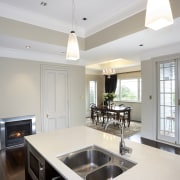 Inner view of this kitchen features fireplace, cabinetry ceiling, countertop, cuisine classique, daylighting, interior design, kitchen, real estate, room, window, white, gray