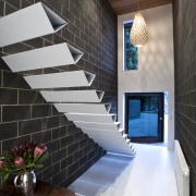 View of cantilevered, triangular-shaped steel stairs, tiled floors, apartment, architecture, ceiling, daylighting, estate, floor, flooring, handrail, home, house, interior design, lobby, real estate, room, stairs, tile, wall, black