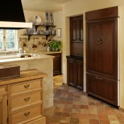 View of French-styled farmhouse kitchen which features antique cabinetry, countertop, cuisine classique, floor, flooring, hardwood, home, interior design, kitchen, laminate flooring, room, tile, wood, wood flooring, wood stain, brown, orange