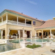 Exterior view of an Italian villa-styled waterfront home. elevation, estate, facade, hacienda, home, house, mansion, property, real estate, residential area, resort, roof, swimming pool, villa, window, teal