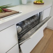 View of open dishwasher in contemporary light-toned kitchen. countertop, drawer, floor, furniture, home appliance, kitchen, kitchen appliance, kitchen stove, major appliance, product design, gray