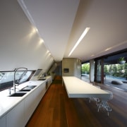 View of kitchen area featuring hardwood flooring, island apartment, architecture, ceiling, daylighting, house, interior design, gray