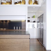 View of contemporary kitchen with wooden island and cabinetry, countertop, floor, flooring, furniture, hardwood, interior design, kitchen, product design, room, shelf, wood flooring, white, gray