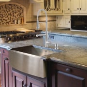 View of a kitchen which features a stainless cabinetry, countertop, cuisine classique, flooring, granite, hardwood, kitchen, kitchen stove, sink, wood stain, gray