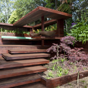 View of timber outdoor seating area with large backyard, deck, house, landscaping, outdoor structure, plant, tree, wood, red