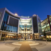 Exterior view of the Robina Town Centre where architecture, building, city, commercial building, condominium, convention center, corporate headquarters, downtown, headquarters, hotel, metropolis, metropolitan area, mixed use, night, plaza, real estate, residential area, shopping mall, sky, blue