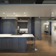 View of an apartment kitchen with dark-toned cabinetry, architecture, ceiling, countertop, floor, flooring, interior design, kitchen, gray, black
