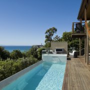 View of pool and spa area with wooden estate, home, house, leisure, property, real estate, resort, sky, swimming pool, vacation, villa, teal, brown