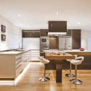 View of a kitchen which features island with cabinetry, countertop, cuisine classique, floor, furniture, interior design, kitchen, office, real estate, room, white, orange