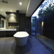 View of dark-toned bathroom with white tub. - architecture, bathroom, ceiling, daylighting, estate, floor, flooring, home, house, interior design, lighting, property, real estate, tile, black, blue