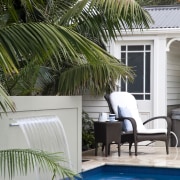 View of outdoor area with pool, paving, fountain, arecales, backyard, estate, home, house, outdoor furniture, outdoor structure, palm tree, plant, property, real estate, resort, sunlounger, swimming pool, tree, water, window, gray