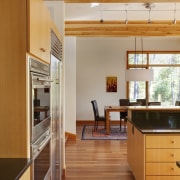 View of sunken open-plan kitchen with wooden cabinetry, architecture, cabinetry, ceiling, countertop, daylighting, floor, flooring, hardwood, house, interior design, kitchen, laminate flooring, real estate, room, wood, wood flooring, brown, orange