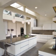 View of neutral-toned kitchen and dining space, featuring cabinetry, countertop, cuisine classique, interior design, kitchen, real estate, room, gray