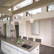 View of neutral-toned kitchen and dining space, featuring cabinetry, ceiling, countertop, cuisine classique, daylighting, interior design, kitchen, gray, brown