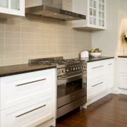 View of kitchen with wooden flooring, dark benchtops cabinetry, countertop, cuisine classique, drawer, floor, flooring, furniture, hardwood, home, home appliance, interior design, kitchen, kitchen appliance, kitchen stove, room, tile, white, brown