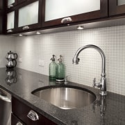 View of kitchen in Art-Deco styled apartment building, cabinetry, countertop, interior design, kitchen, sink, tile, under cabinet lighting, white, black, gray