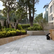 View of outdoor patio area in a contemporary backyard, courtyard, driveway, estate, garden, home, house, landscaping, neighbourhood, outdoor structure, patio, plant, property, real estate, residential area, walkway, wall, yard, brown