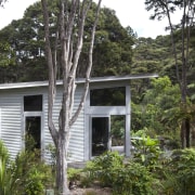 View of contemporary home surrounded by trees. - architecture, cottage, home, house, jungle, plant, property, rainforest, real estate, tree, brown