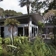 View of contemporary home surrounded by trees. - cottage, estate, home, house, plant, property, real estate, tree, villa, black, brown