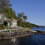 View of waterfront house. - View of waterfront bay, coast, cottage, home, house, inlet, lake, real estate, sea, shore, sky, tree, water, blue