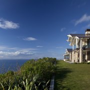 This home was designed by Peter Chibnall of cloud, cottage, estate, grass, home, horizon, house, mansion, property, real estate, sea, sky, villa, blue