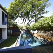 This house was designed by Kon Panagopoulos and backyard, home, house, outdoor structure, plant, property, real estate, resort, swimming pool, tree, water, yard, black