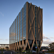 View of the Novotel Auckland Airport in Auckland architecture, building, corporate headquarters, facade, headquarters, landmark, sky, skyscraper, structure, tower block, teal