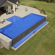 This is a view of the pool designed backyard, grass, house, lawn, leisure, outdoor furniture, property, real estate, roof, sunlounger, swimming pool, yard, brown
