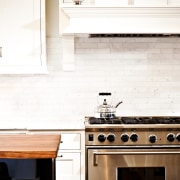 View of kitchen designed by Nadia Subaran. Designed cabinetry, countertop, floor, flooring, furniture, hardwood, home, home appliance, interior design, kitchen, kitchen stove, room, under cabinet lighting, white