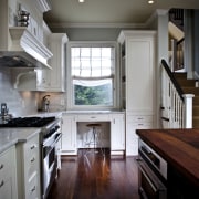 View of kitchen designed by Nadia Subaran. Designed cabinetry, ceiling, countertop, cuisine classique, floor, flooring, hardwood, home, interior design, kitchen, room, under cabinet lighting, window, wood, wood flooring, black, gray