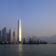 Here is a view of the ICC (International body of water, calm, city, cityscape, dawn, daytime, dusk, evening, haze, horizon, metropolis, metropolitan area, morning, reflection, river, sea, sky, skyline, skyscraper, sunset, tower, tower block, water, blue, gray