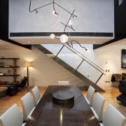 View of dining area in contemporary apartment. - architecture, ceiling, floor, home, interior design, light fixture, lighting, living room, loft, product design, table, wall, gray, black