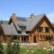 This large home efficiently uses solar energy thanks cottage, elevation, estate, facade, farmhouse, home, house, hut, log cabin, property, real estate, roof, siding, window, wood, teal, brown