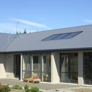 This large home efficiently uses solar energy thanks daylighting, facade, home, house, property, real estate, roof, siding, window, teal