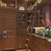 View of kitchen with wooden cabinetry and ladder. cabinetry, flooring, furniture, hardwood, room, shelving, wood, wood stain, brown