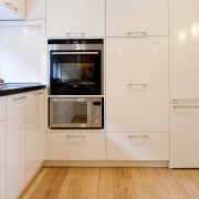 View of contemporary kitchen with white cabinetry and cabinetry, countertop, cuisine classique, floor, flooring, hardwood, home appliance, kitchen, kitchen appliance, major appliance, property, room, white