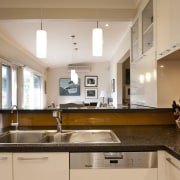 View of contemporary kitchen with white cabinetry, dark countertop, interior design, kitchen, real estate, room, brown, orange, white