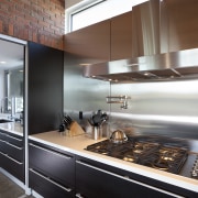 brick walls  above rangehood and cooktop, black cabinetry, countertop, cuisine classique, interior design, kitchen, gray
