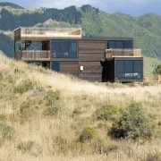 View of contemporary home on tussocky slope. - architecture, home, house, land lot, landscape, prairie, property, real estate, rural area, shack, shed, sky, orange