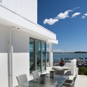 Situated to one side of this house, yet apartment, architecture, condominium, daylighting, home, house, interior design, outdoor furniture, property, real estate, sky, sunlounger, table, white