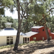 View of red and white buildings with trees. cottage, home, house, hut, plant, property, real estate, tree