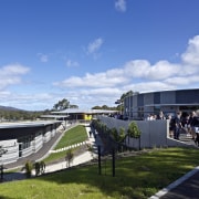 View of exterior with landscaping. - View of architecture, city, corporate headquarters, mixed use, real estate, sky, sport venue, structure, tree, teal