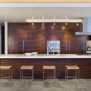 Kitchen area with bar stools. - Kitchen area cabinetry, ceiling, countertop, flooring, furniture, interior design, kitchen, lobby, wall, gray